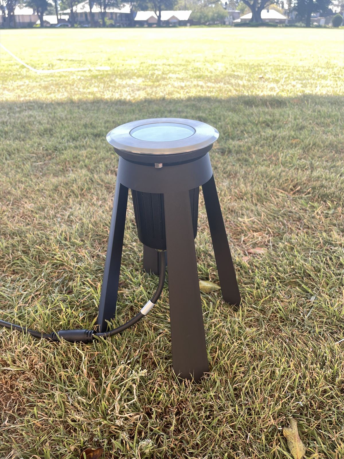 Tripod stand holding a garden light on a lawn