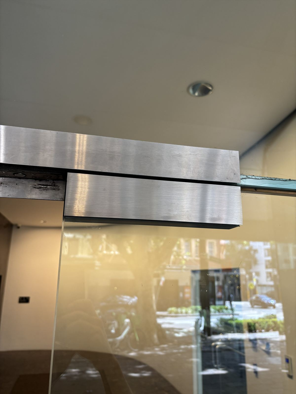 Metal fitting installed above a glass door, CNC machined from a WITT design